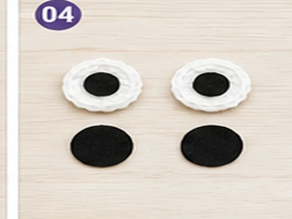 Two white crochet eyes with black felt centers before attachment
